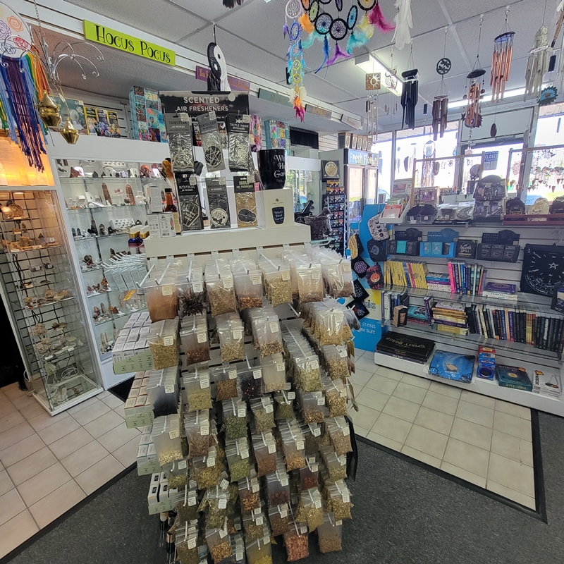 View from the centre of The Zen Shop Oshawa showing an extensive herbal display alongside shelves of metaphysical books, pendulums, and surrounding crystal cabinets near the front window.