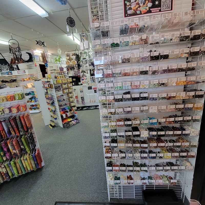 Mid-store view at The Zen Shop Oshawa featuring organized tumbled crystal bins with QR codes linking to each stone’s meaning, alongside Hem incense and candle displays near the north wall.
