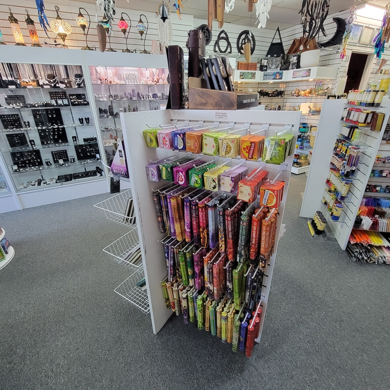 Mid-store view at The Zen Shop Oshawa featuring a vibrant Hem incense display, with showcases of sterling silver rings, chains, earrings, and symbolic pendants, alongside dream catchers and spiritual candles.