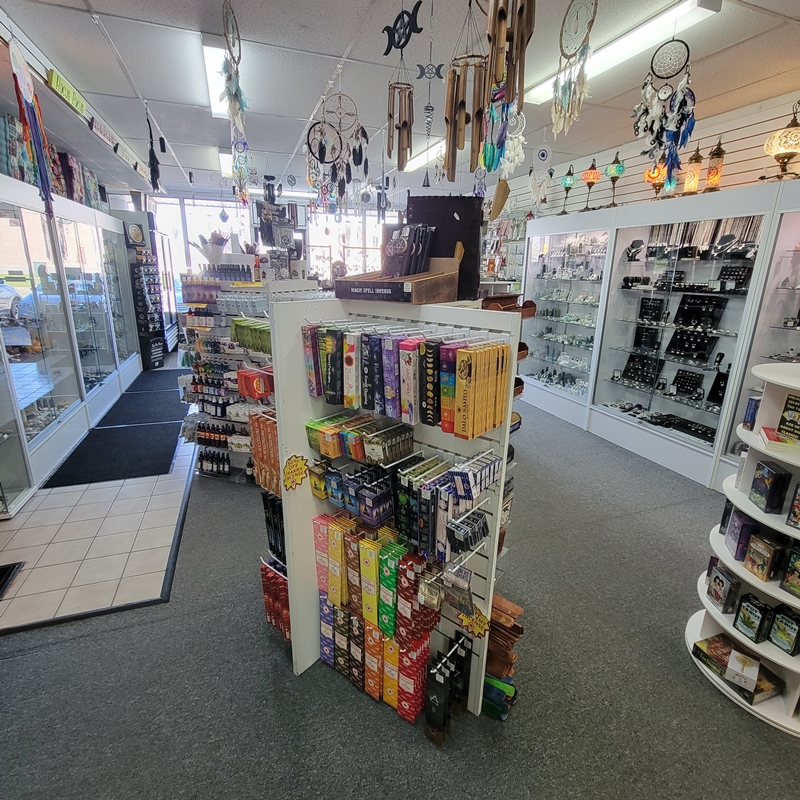 Mid-store view at The Zen Shop Oshawa showcasing Green Tree and Champa incense, a rotating tarot card display, spiritual sprays and oils in the background, and sterling silver jewellery cabinets. Dreamcatchers and wind chimes hang beautifully from the ceiling, adding to the shop’s magical ambience.